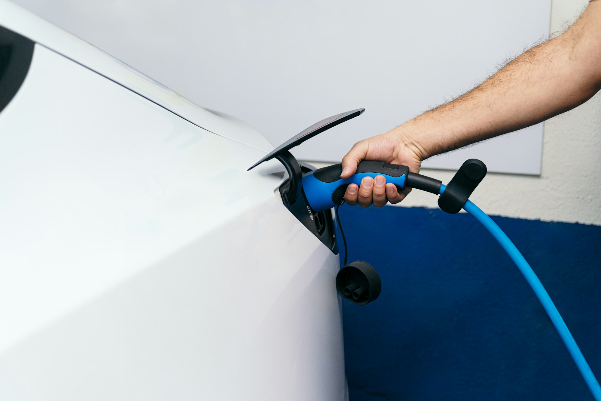 Unrecognizable Man's Arm Plugging Charger into Electric Car