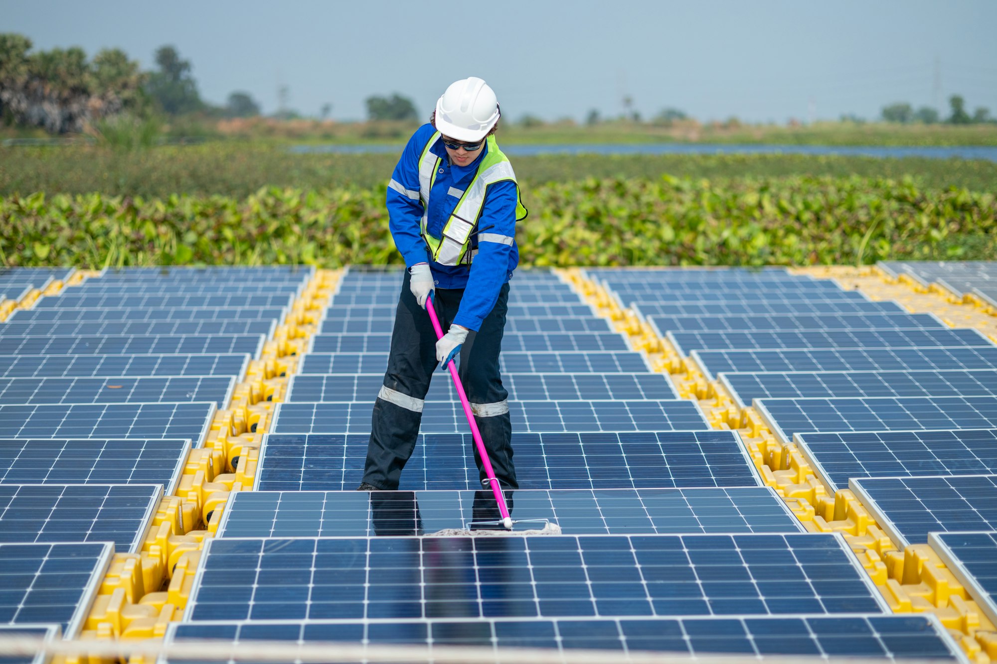 Worker Cleaning Solar Panels at Renewable Energy Farm